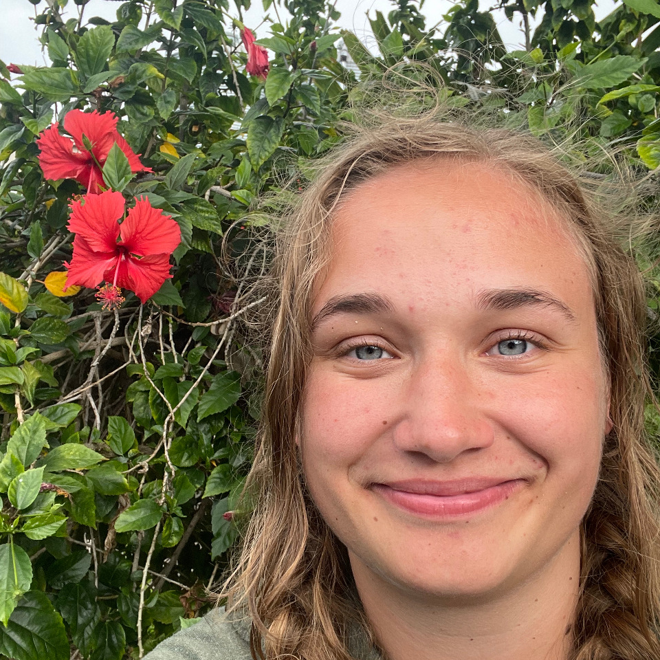 Sierra Wylde posing next to a red hibiscus flower.